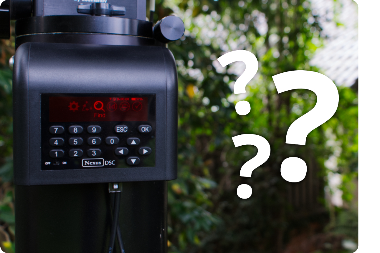 A Nexus DSC installed on a large mount with foliage in the background. Next to the DSC are three white question marks in various sizes.